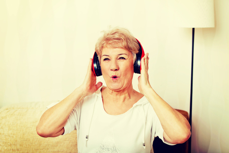 Happy senior woman wearing red headphonesの写真素材