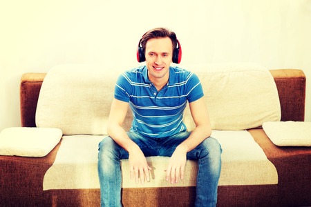 Happy man sitting on sofa and listening musicの写真素材