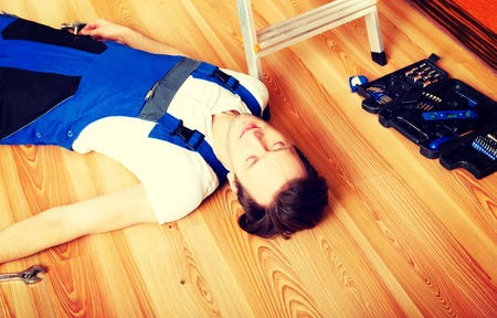 Young handyman fell from a ladder and lies on the floorの写真素材
