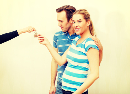 Real estate agent giving keys to the coupleの写真素材