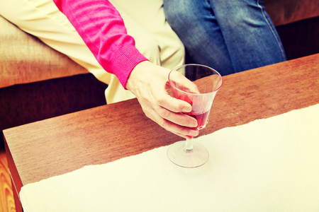 Senior woman put glass of wine on tableの写真素材