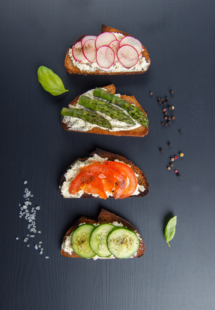 Four different sandwiches on black board.の写真素材