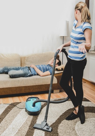 Woman doing woman chores at home. Vacumming the carpetの写真素材