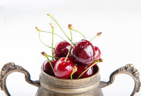 Juicy wet cherries in brass vessel.の写真素材