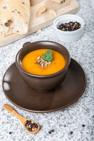 Brown cup with squash soup, roll with olives.の写真素材