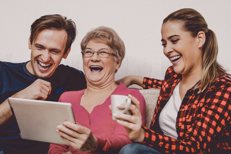 Happy adult kids with elderly mother on couch.の写真素材
