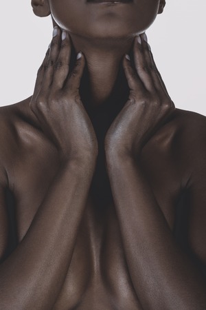 Statuesque cleavage of nude black mixed race woman covering breast.の写真素材