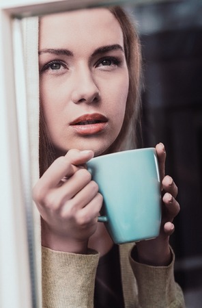 Pensive woman in windowの写真素材
