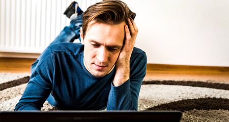 Exhausted man working on laptopの写真素材