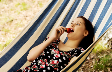 Woman eating strawberry in hammockの写真素材