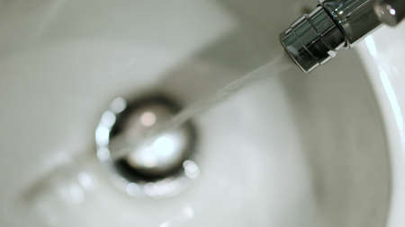 The close-up of a stream of water falling into a ceramic bidet bowl. Bathroom fittings. Hygiene in the toilet. Cleanliness after using the toilet. Turn off the tap.の写真素材