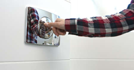 Woman hand pressing a button to flush toilet after using.の写真素材