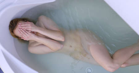 Relaxed woman lying in bath washing her hair.の写真素材