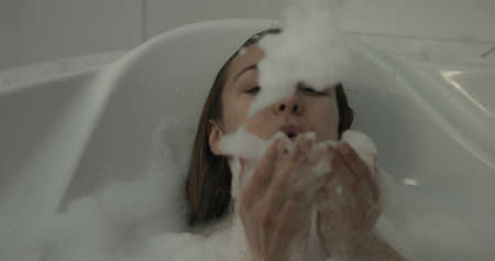Woman taking bath in bathtub at bathroomの写真素材