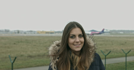 Woman looking at camera and smiling. Airport in background.