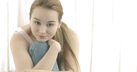 Beautiful smiling woman looking at camera at home in the living roomの写真素材