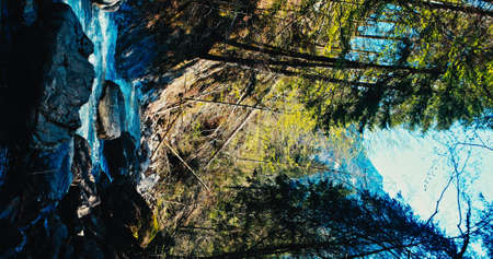 A river flows over rocks in this beautiful scene in the Alps mountains in spring. Vertical 4kの写真素材