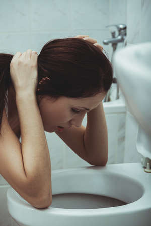 Woman vomiting in the bathroom.の写真素材