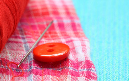 Red button on a cotton cloth with needle