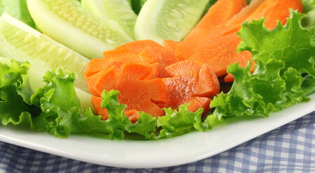 Salad of cucumbers, carrots and lettuce on plateの写真素材
