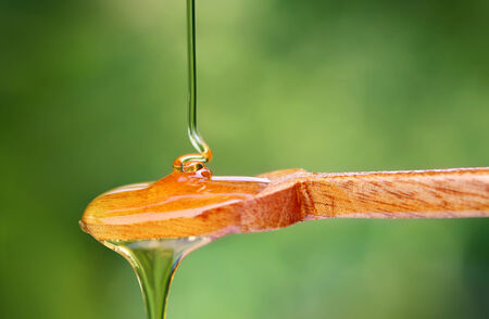 Closeup of dripping honey on wooden spoon の写真素材