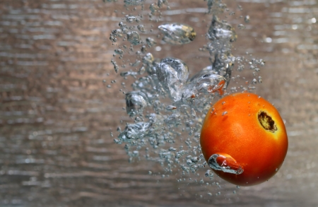 Water splash of a red tomato in an aquariumの写真素材