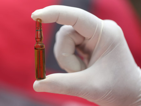 Close up of an ampoule holding by hand with glovesの写真素材