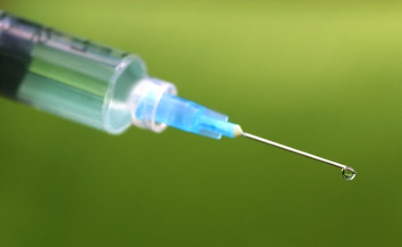 Close up of Hypodermic syringe falling herbal dropの写真素材