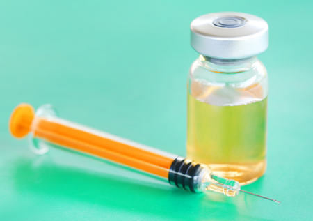 Syringe with vial on green surfaceの写真素材