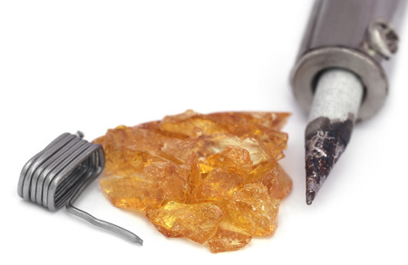 Soldering iron with spool of solder and resin over white backgroundの写真素材