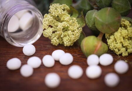 Homeopathy globules with some herbs on wooden surfaceの写真素材