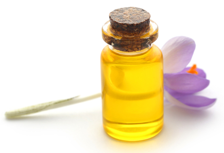 Saffron crocus flower with extract in a bottle over whiteの写真素材
