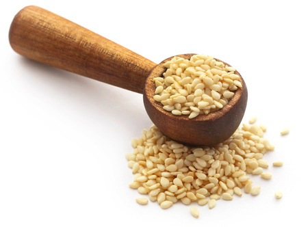 Peeled sesame seeds in a spoon over white backgroundの写真素材