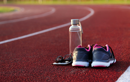Water bottle and shoes on athletic track at afternoonの写真素材