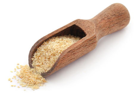 Garlic powder in a wooden scoop over white backgroundの写真素材