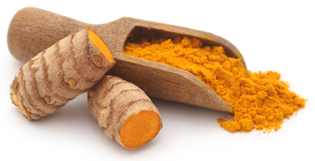 Raw turmeric with powder in a wooden scoop over white backgroundの写真素材