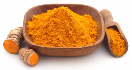 Raw turmeric with powder in small bowl over white backgroundの写真素材