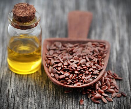 Flax seeds with oil in a glass jar on wooden surfaceの写真素材