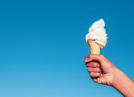 Hand holding an icecream against blue sky