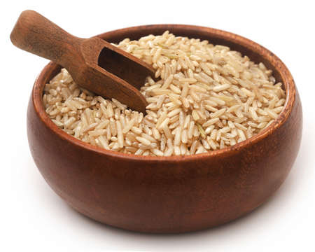 Uncooked brown rice in a bowl over whiteの写真素材