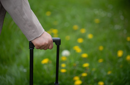 Hand holding a trolley bag handle against green grass