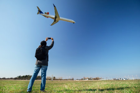 Girl taking photo of an aircraft landing at Copenhagen Airportの写真素材