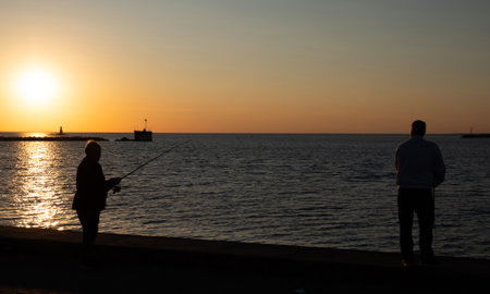 Silhouette of two anglers fishing at Malmo horbor at late afternoonの写真素材