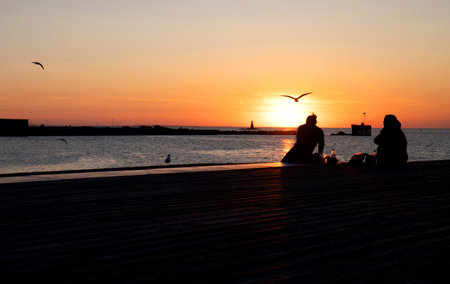 Silhouette of two women at Malmo harbor at late afternoonの写真素材