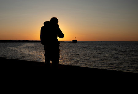 Silhouette of a photographer in action at Malmo harbor during late afternoonの写真素材
