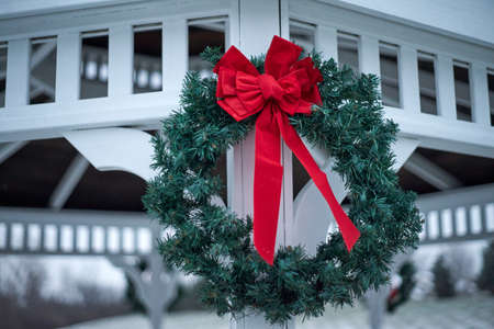 Green Christmas wreat with red bow hanging on outside gazebo.の写真素材