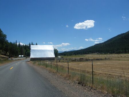 Country barn and pasture next to the road with blue sky and cloudsの写真素材