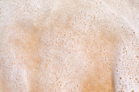 Close up picture of a wave's foam on a sandy beach in Bali