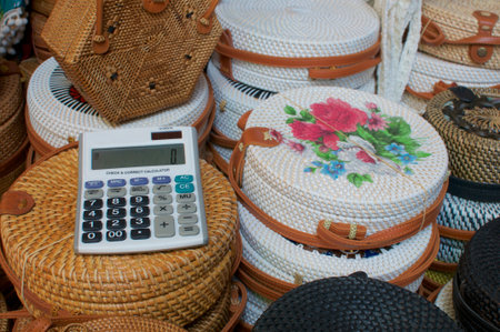 Close up picture of an calculator on a group of brown and white rattan bags displayed at the Ubud...