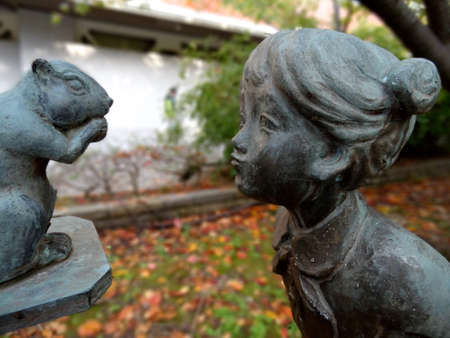Close up picture of a beautiful bronze statue of a little girl that admires a squirrel, located on Port Island in Kobeの写真素材